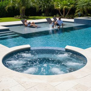 A view of an integrated, heated circular spa bubbling next to a pool, with a shallow sun shelf (tanning ledge) and two submerged lounge chairs, emphasizing relaxation and functionality.